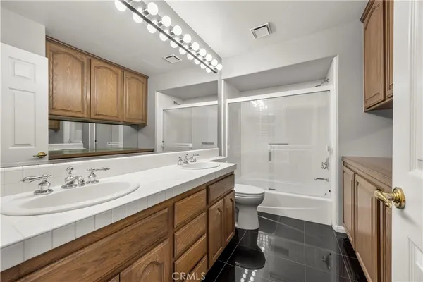 a bathroom with a sink a toilet a mirror and shower