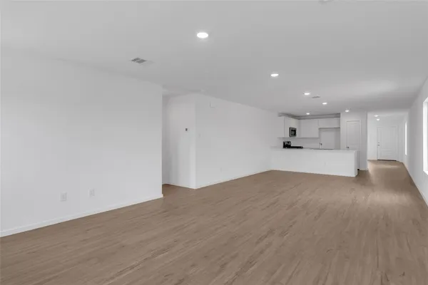 a view of kitchen and empty room with wooden floor