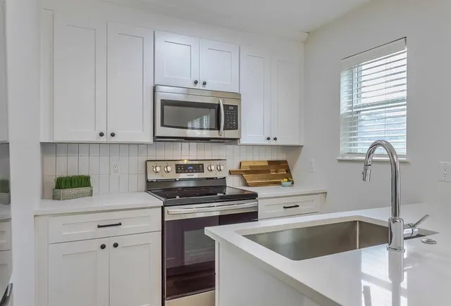 a kitchen with white cabinets and a stove top oven