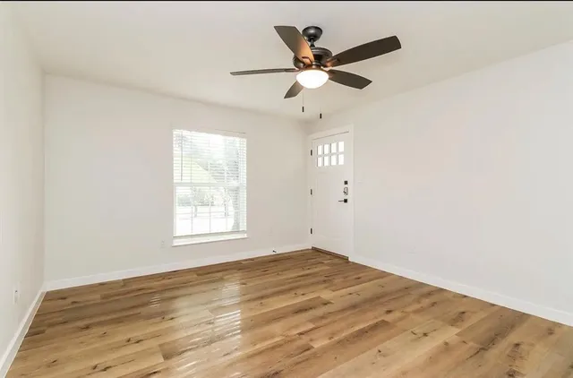a view of a big room with wooden floor and windows