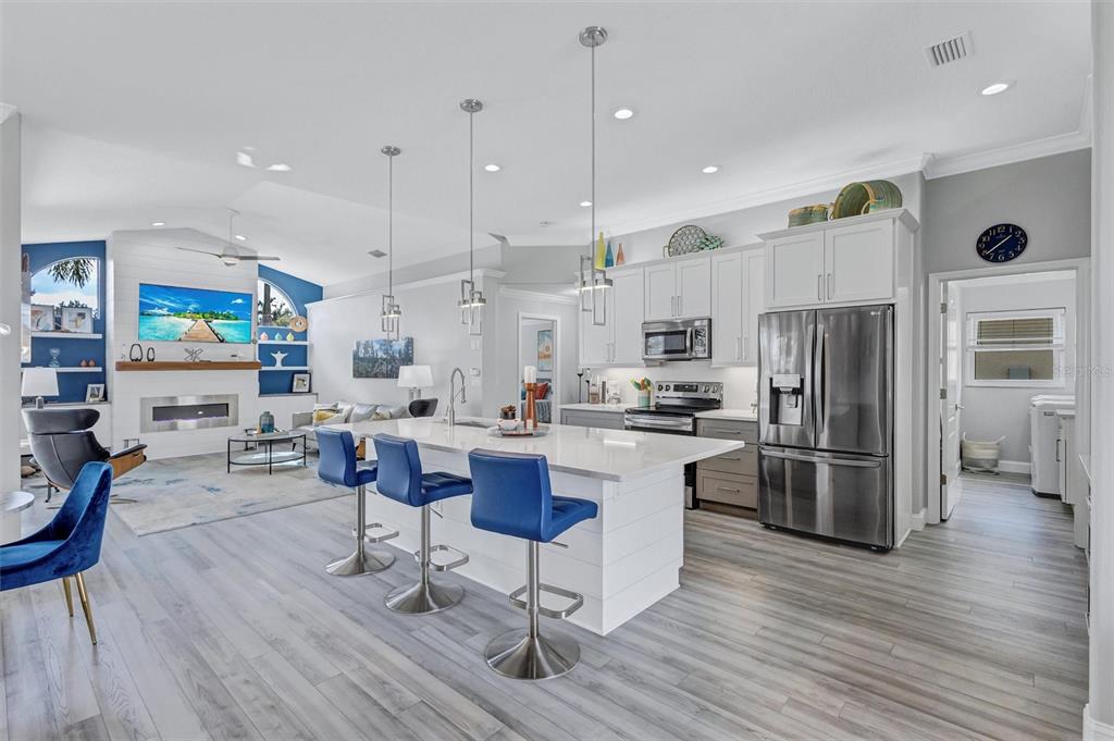 8409 29th Street East Parrish, FL 34219 - Photo 16 of 65 a kitchen with stainless steel appliances kitchen island granite countertop a refrigerator a stove top oven a sink cabinets and wooden floor