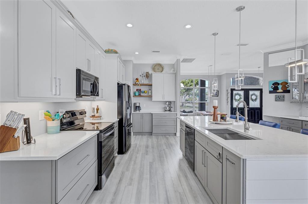 8409 29th Street East Parrish, FL 34219 - Photo 17 of 65 a kitchen with stainless steel appliances kitchen island granite countertop a sink a stove a refrigerator and white cabinets