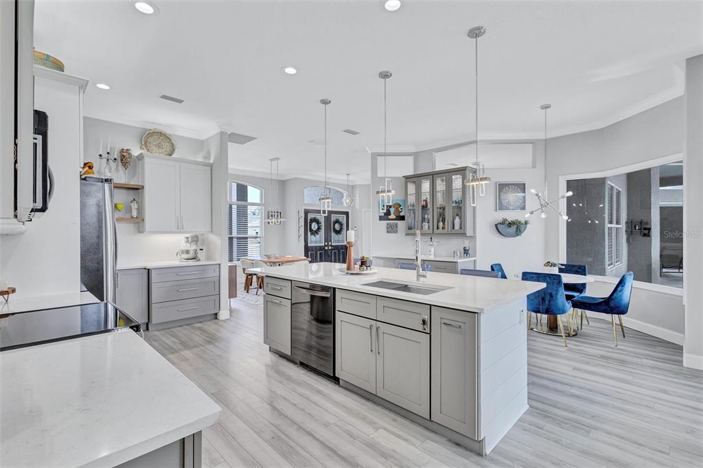 8409 29th Street East Parrish, FL 34219 - Photo 18 of 65 a large kitchen with stainless steel appliances kitchen island a stove a sink dishwasher a refrigerator and white cabinets with wooden floor