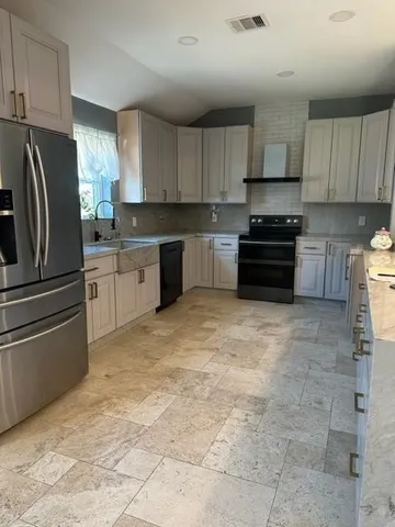 a kitchen with granite countertop a refrigerator and a stove top oven
