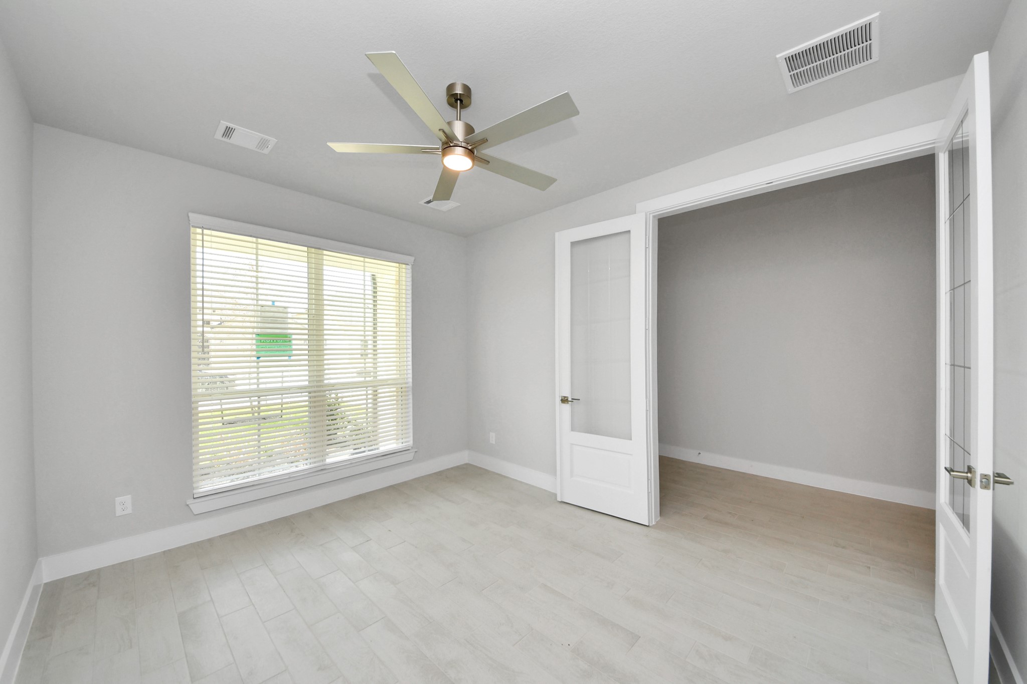 3043 Native Spg Drive Spring, TX 77373 - Photo 7 of 45 Experience the perfect blend of sophistication and warmth in this home office, boasting elegant wood-look tile flooring and flooded with natural light from expansive windows and French doors.