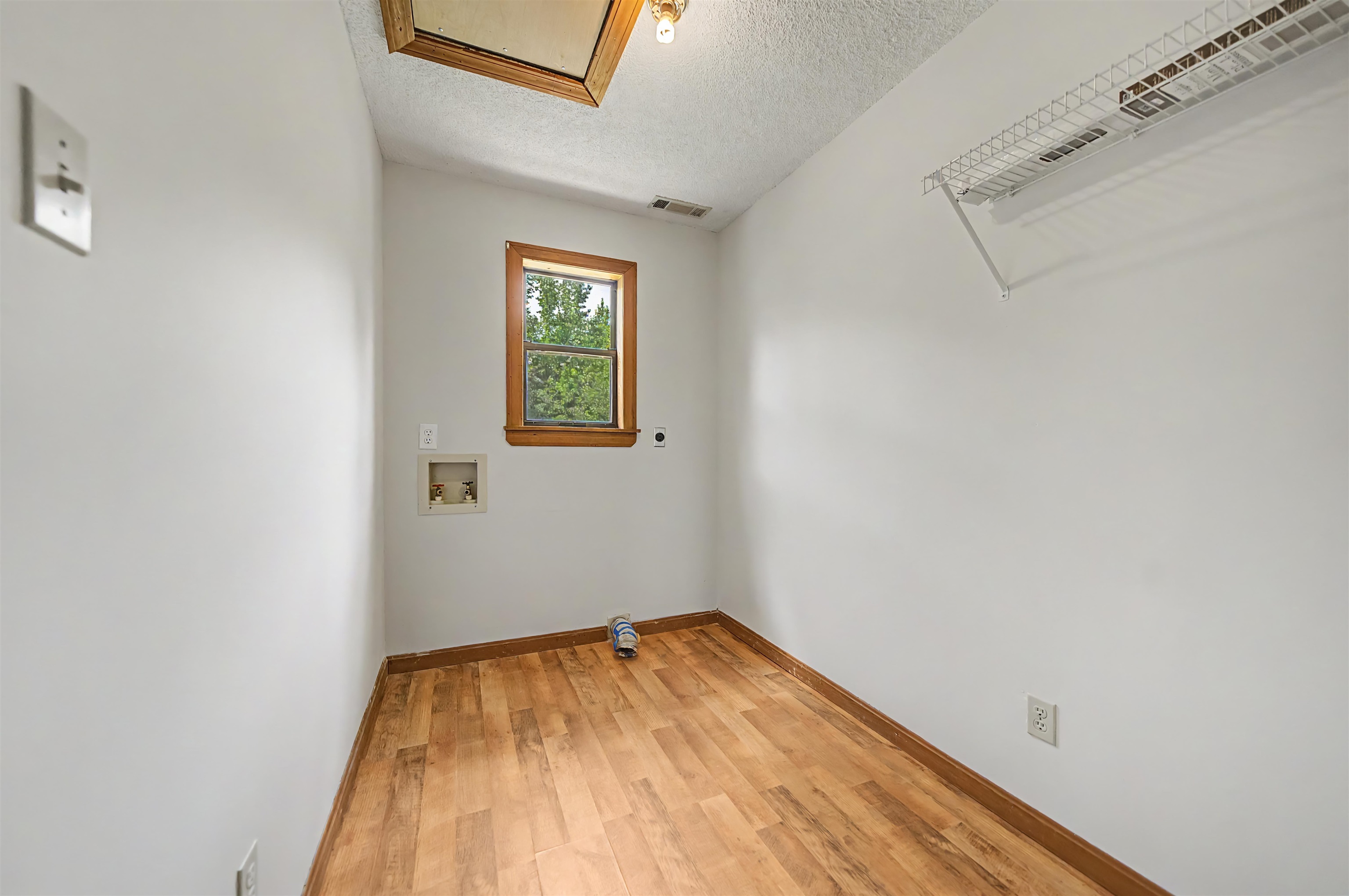 2380 Dunaway Road Selmer, TN 38375 - Photo 28 of 39 Laundry room with wood-finish flooring, a window, and a built-in wire shelf