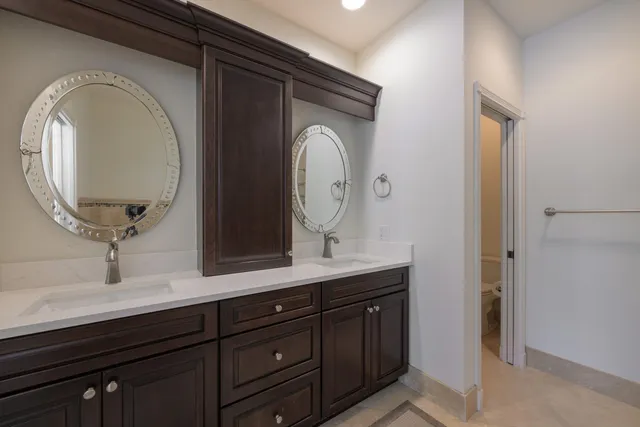 a bathroom with a granite countertop double vanity sink and a mirror