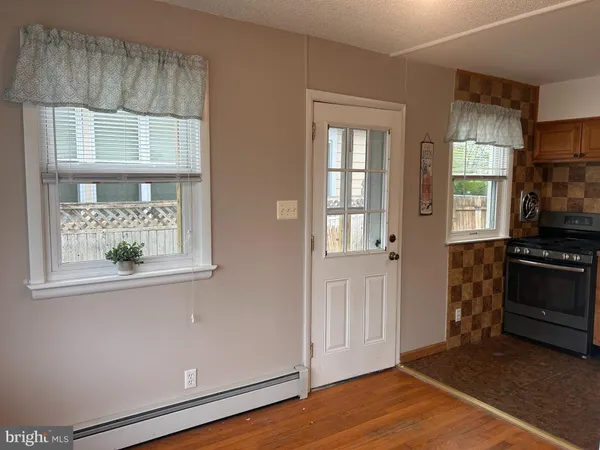 an empty room with wooden floor cabinet and windows