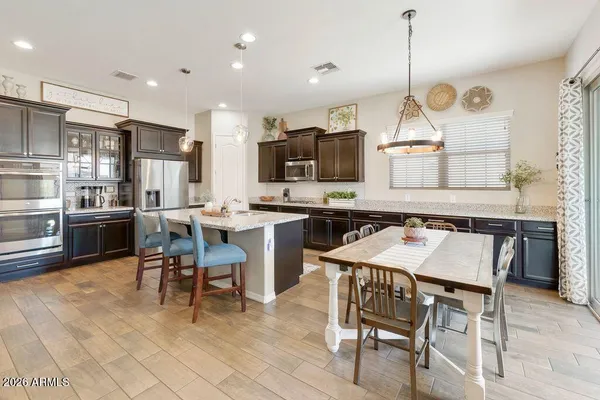 a kitchen with stainless steel appliances kitchen island granite countertop a table chairs sink and cabinets