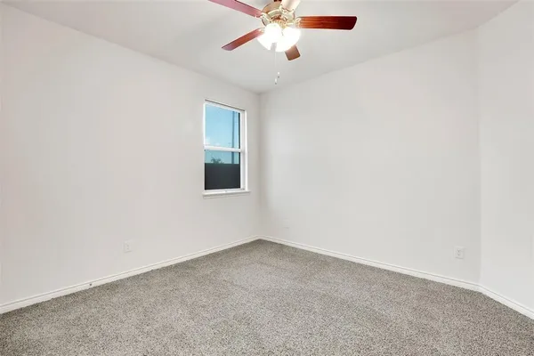 an empty room with a window and a fan