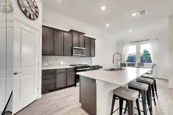 a kitchen with sink a stove and chairs