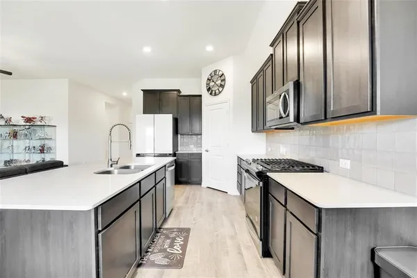 a kitchen with stainless steel appliances granite countertop a sink a stove and a refrigerator
