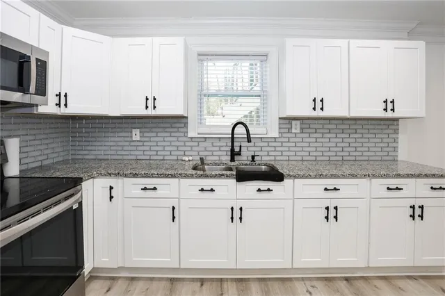 a kitchen with white cabinets and sink