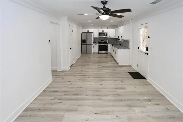 a view of a hallway with wooden floor and ceiling fan