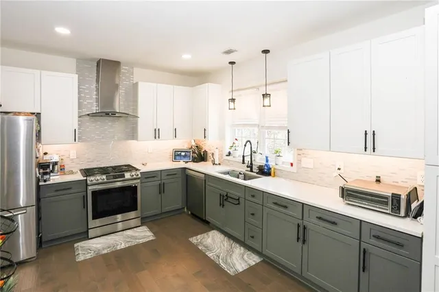 a kitchen with stainless steel appliances a stove a sink and white cabinets
