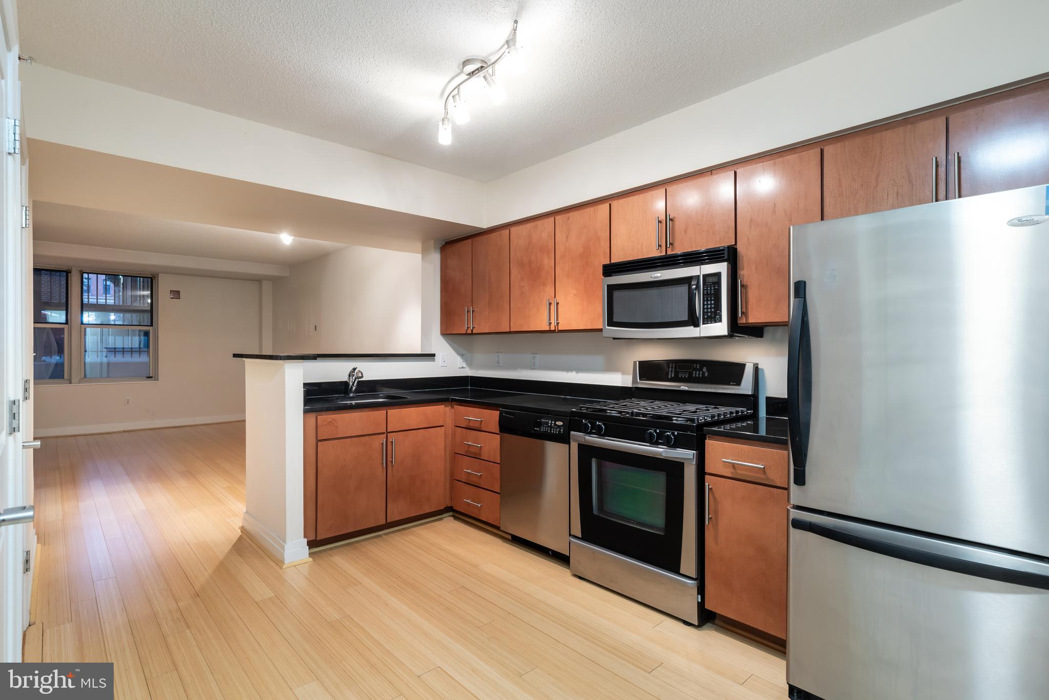 915 E Street Northwest, Unit 103 Washington, DC 20004 - Photo 9 of 43 a kitchen with granite countertop wooden floors a refrigerator and a stove