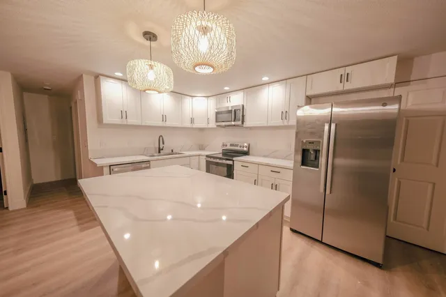 a kitchen with kitchen island a counter top space a refrigerator and cabinets