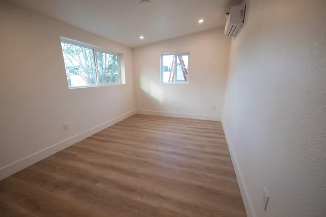 an empty room with wooden floor and windows