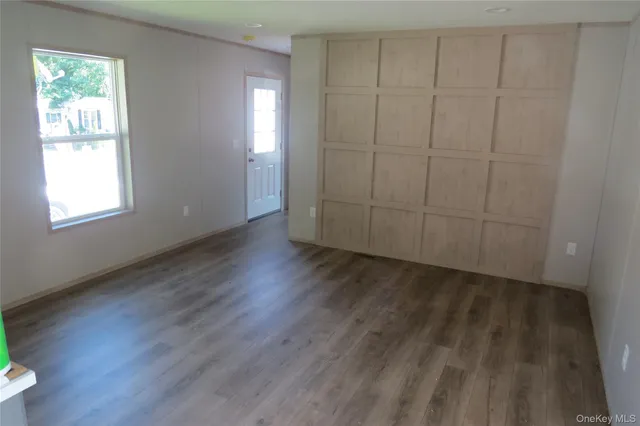 an empty room with wooden floor closet and windows