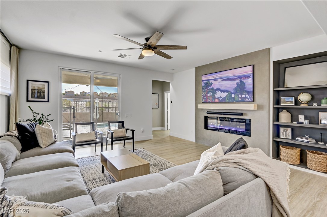 2835 Strathallan Avenue Henderson, NV 89044 - Photo 11 of 64 Living area featuring wood finished floors, built in shelves, a glass covered fireplace, and ceiling fan