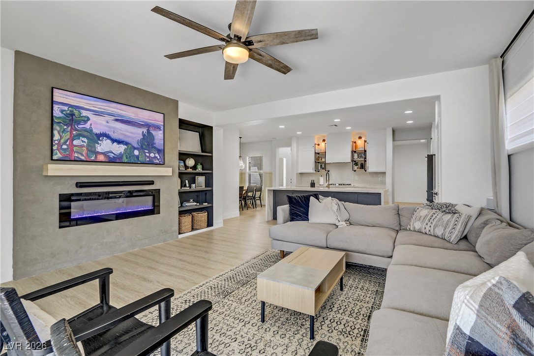 2835 Strathallan Avenue Henderson, NV 89044 - Photo 13 of 64 Living area featuring light wood-style flooring, built in features, a glass covered fireplace, a ceiling fan, and recessed lighting