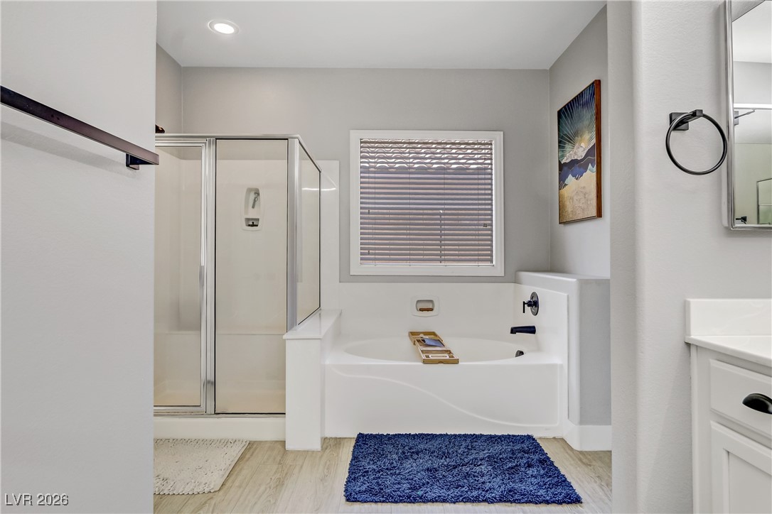 2835 Strathallan Avenue Henderson, NV 89044 - Photo 24 of 64 Full bath featuring vanity, a shower stall, a garden tub, and light wood-type flooring