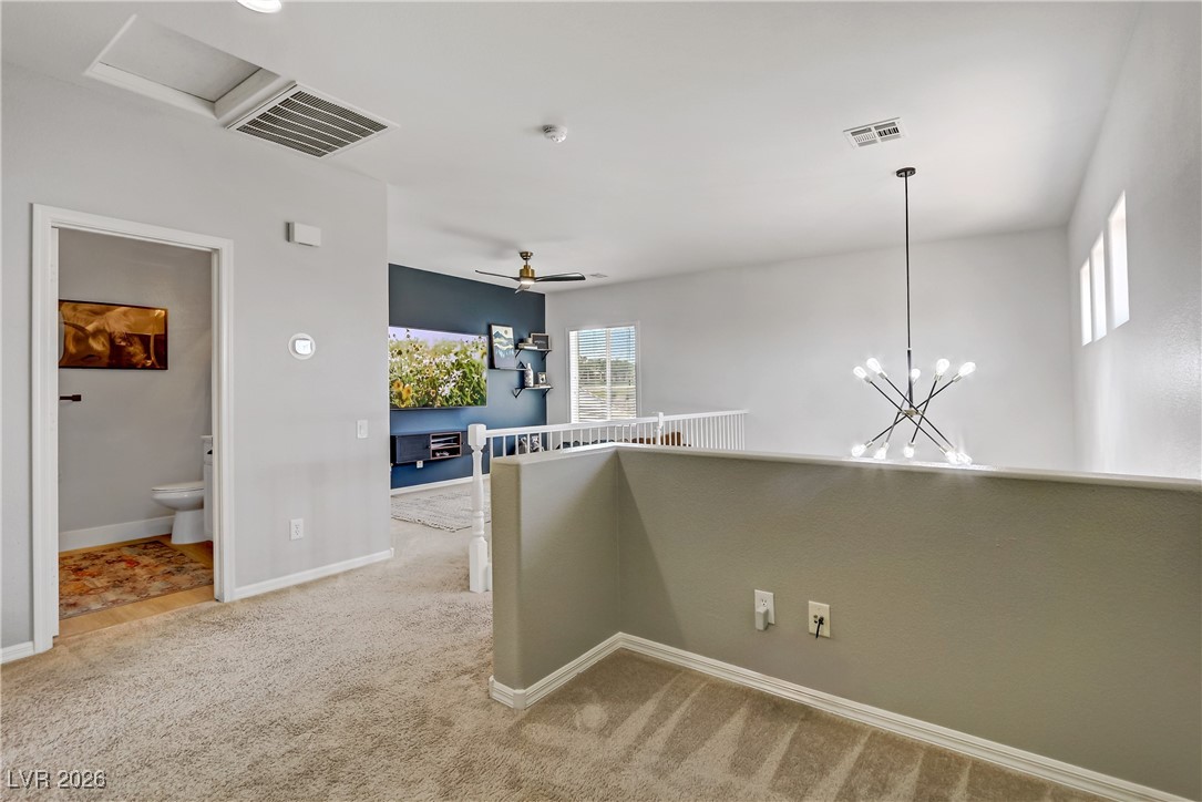 2835 Strathallan Avenue Henderson, NV 89044 - Photo 35 of 64 Hallway with light carpet, a chandelier, attic access, and an upstairs landing
