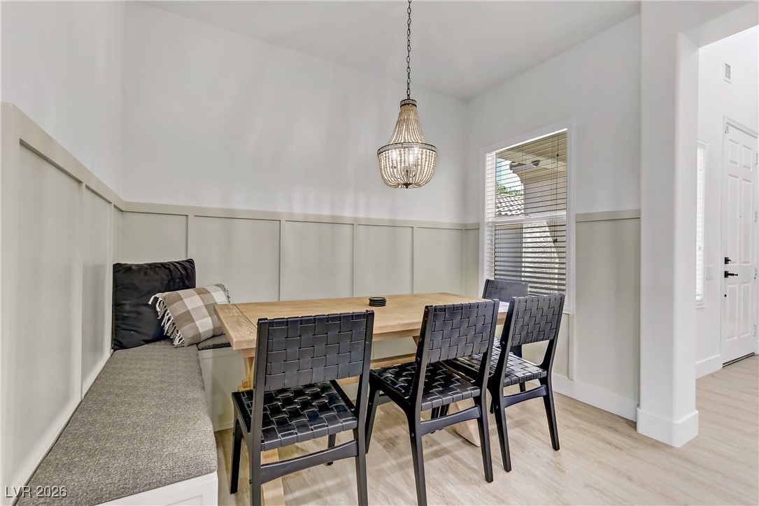 2835 Strathallan Avenue Henderson, NV 89044 - Photo 9 of 64 Dining room featuring light wood-style flooring, a chandelier, and a wainscoted wall