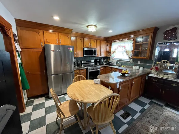 a kitchen with stainless steel appliances granite countertop a refrigerator a sink a stove a dining table and chairs with wooden floor