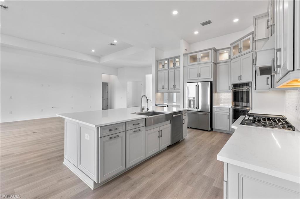 15564 Montello Lane Naples, FL 34114 - Photo 11 of 49 a kitchen with white cabinets and stainless steel appliances