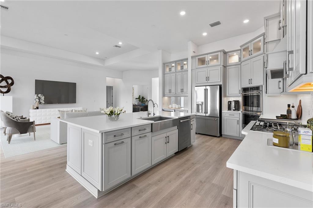 15564 Montello Lane Naples, FL 34114 - Photo 12 of 49 a kitchen with stainless steel appliances a stove a sink a refrigerator white cabinets and wooden floor