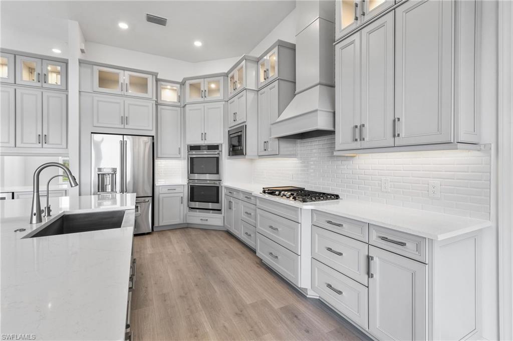 15564 Montello Lane Naples, FL 34114 - Photo 13 of 49 a kitchen with stainless steel appliances granite countertop a stove a sink dishwasher and a refrigerator with white cabinets