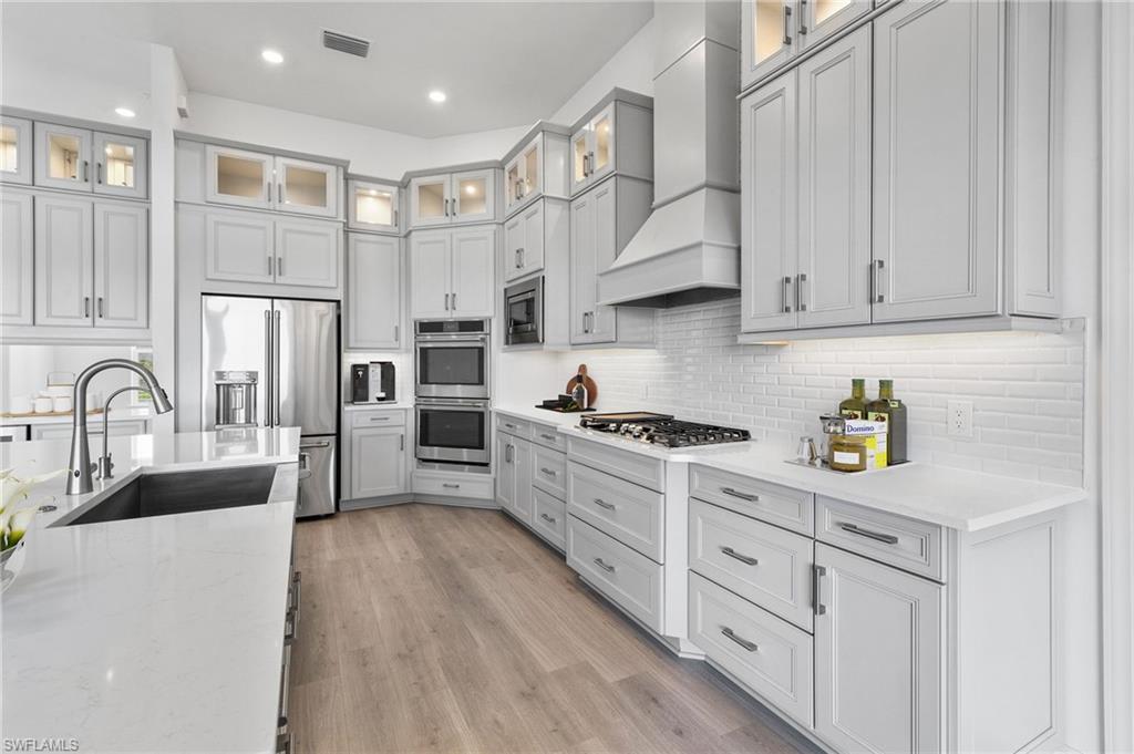 15564 Montello Lane Naples, FL 34114 - Photo 14 of 49 a large kitchen with stainless steel appliances granite countertop a lot of counter space and wooden floors
