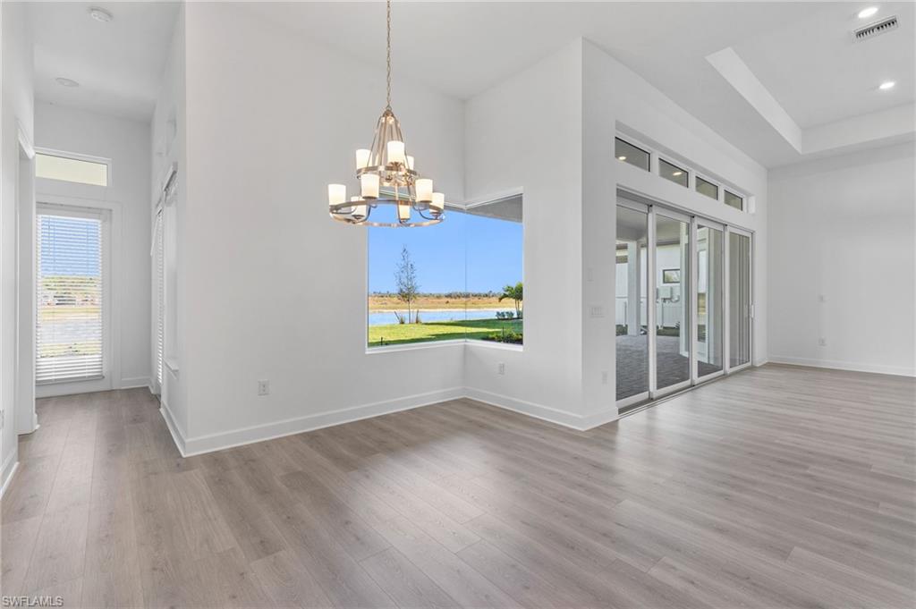 15564 Montello Lane Naples, FL 34114 - Photo 15 of 49 a view of a room with wooden floor chandelier and windows