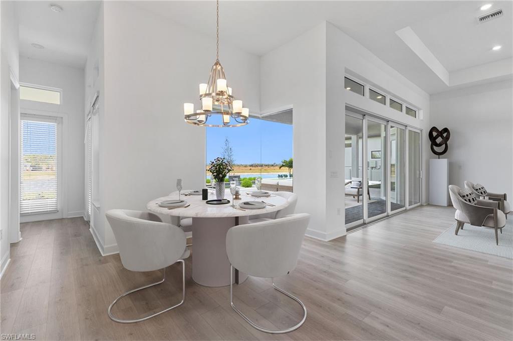 15564 Montello Lane Naples, FL 34114 - Photo 16 of 49 a dining room with furniture a chandelier and wooden floor