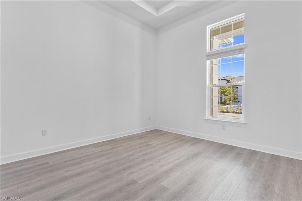 15564 Montello Lane Naples, FL 34114 - Photo 17 of 49 a view of an empty room with wooden floor and a window