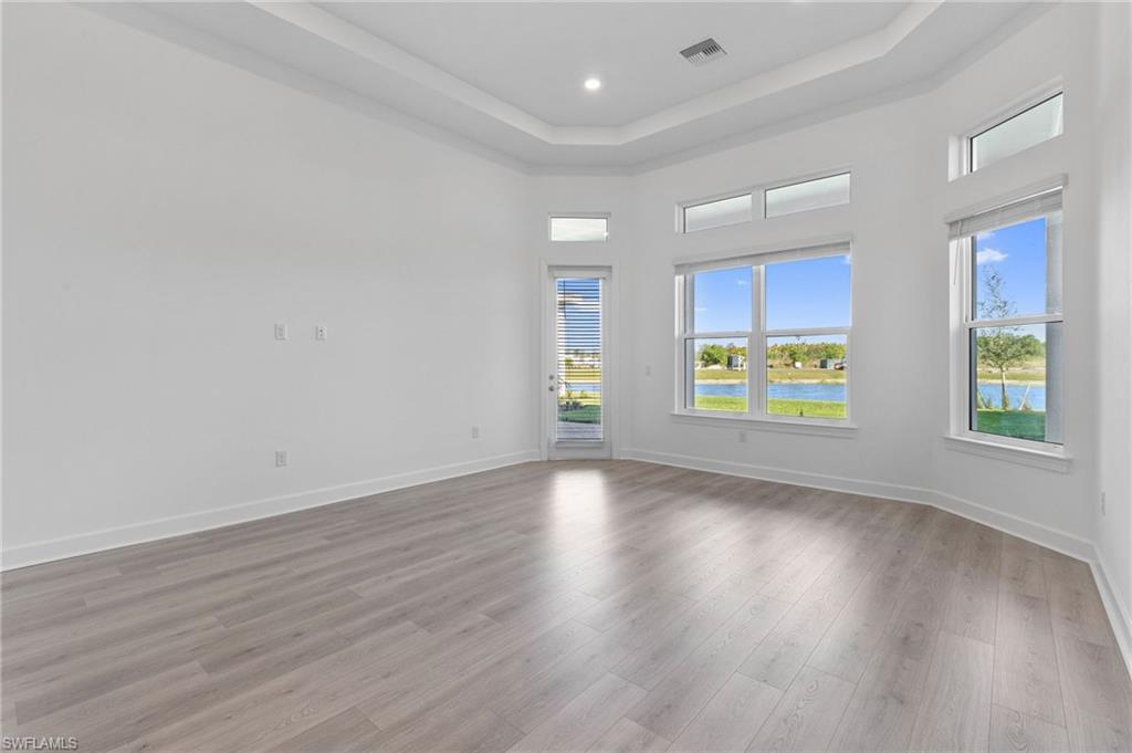 15564 Montello Lane Naples, FL 34114 - Photo 25 of 49 an empty room with wooden floor and windows