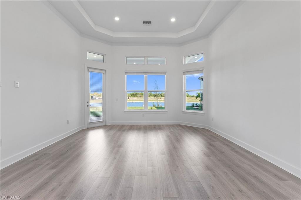 15564 Montello Lane Naples, FL 34114 - Photo 27 of 49 an empty room with wooden floor and windows