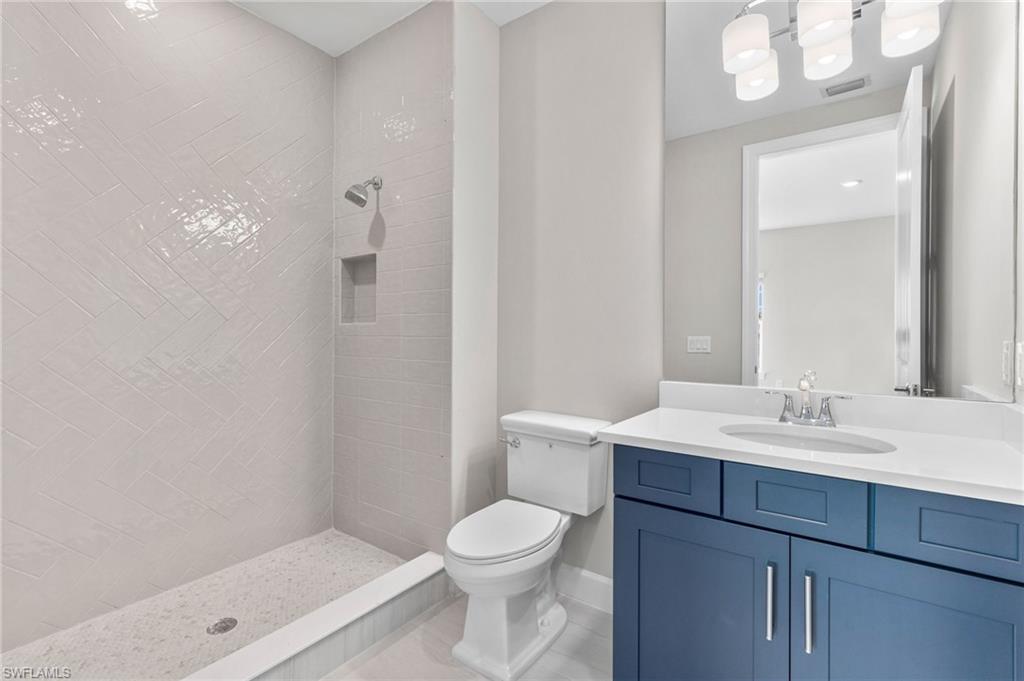 15564 Montello Lane Naples, FL 34114 - Photo 35 of 49 a bathroom with a toilet a sink a mirror and vanity