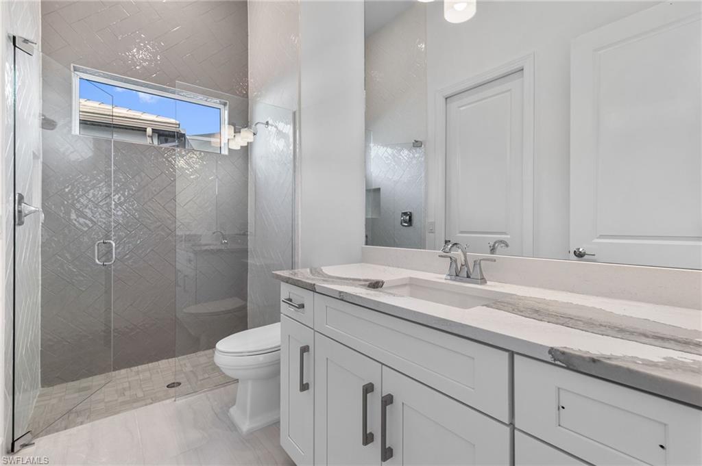 15564 Montello Lane Naples, FL 34114 - Photo 38 of 49 a bathroom with a granite countertop sink a toilet and a shower