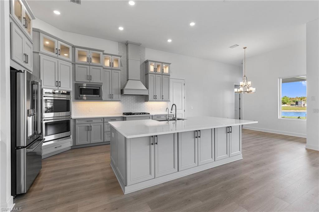 15564 Montello Lane Naples, FL 34114 - Photo 7 of 49 a kitchen with stainless steel appliances a sink cabinets and wooden floor