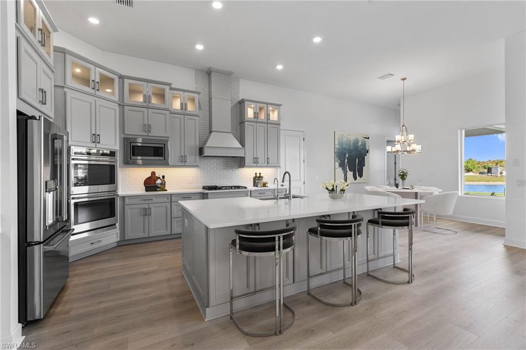 15564 Montello Lane Naples, FL 34114 - Photo 8 of 49 a kitchen with stainless steel appliances granite countertop a table chairs sink refrigerator and cabinets