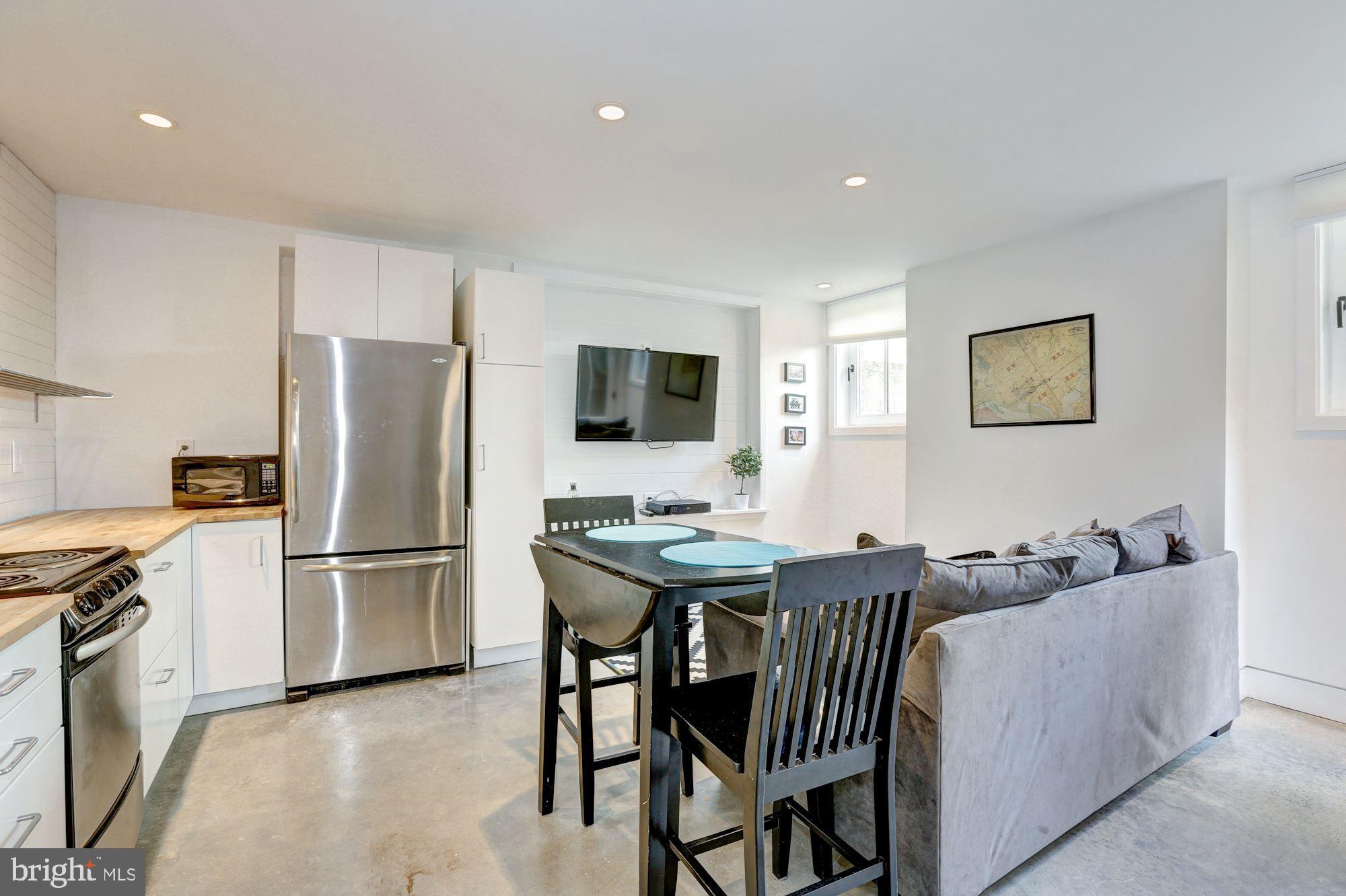 400 U Street Northwest, Unit LL Washington, DC 20001 - Photo 2 of 10 a kitchen with stainless steel appliances granite countertop a stove a refrigerator a sink a dining table and chairs with wooden floor