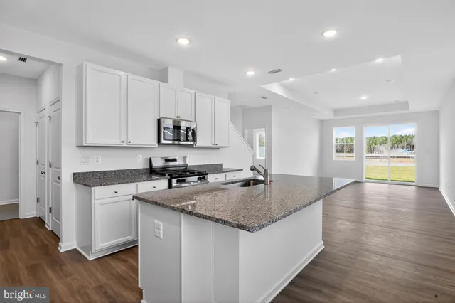 a kitchen with stainless steel appliances granite countertop a sink stove and wooden floor