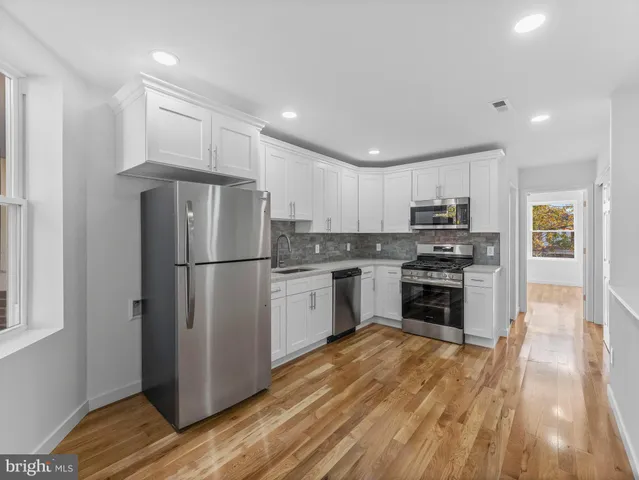 a kitchen with a refrigerator a stove top oven and wooden floor