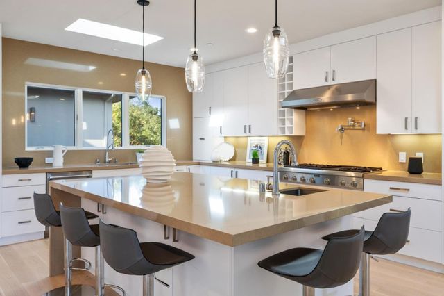 a kitchen with stainless steel appliances kitchen island granite countertop a refrigerator and a dining table