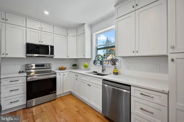 a kitchen with stainless steel appliances granite countertop a sink a stove and dishwasher with white cabinets