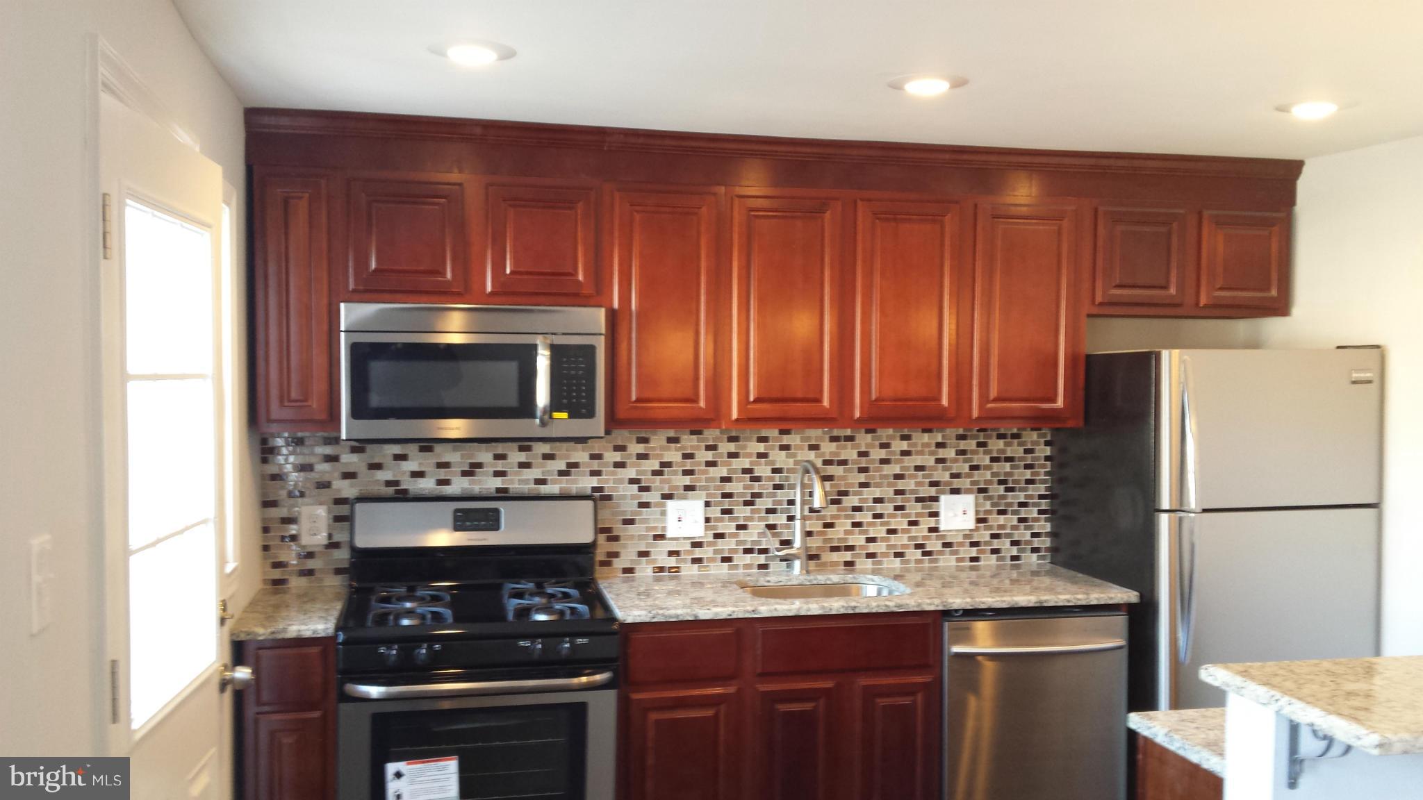 1111 Wicklow Road Baltimore, MD 21229 - Photo 1 of 15 a kitchen with wooden cabinets and a stove top oven