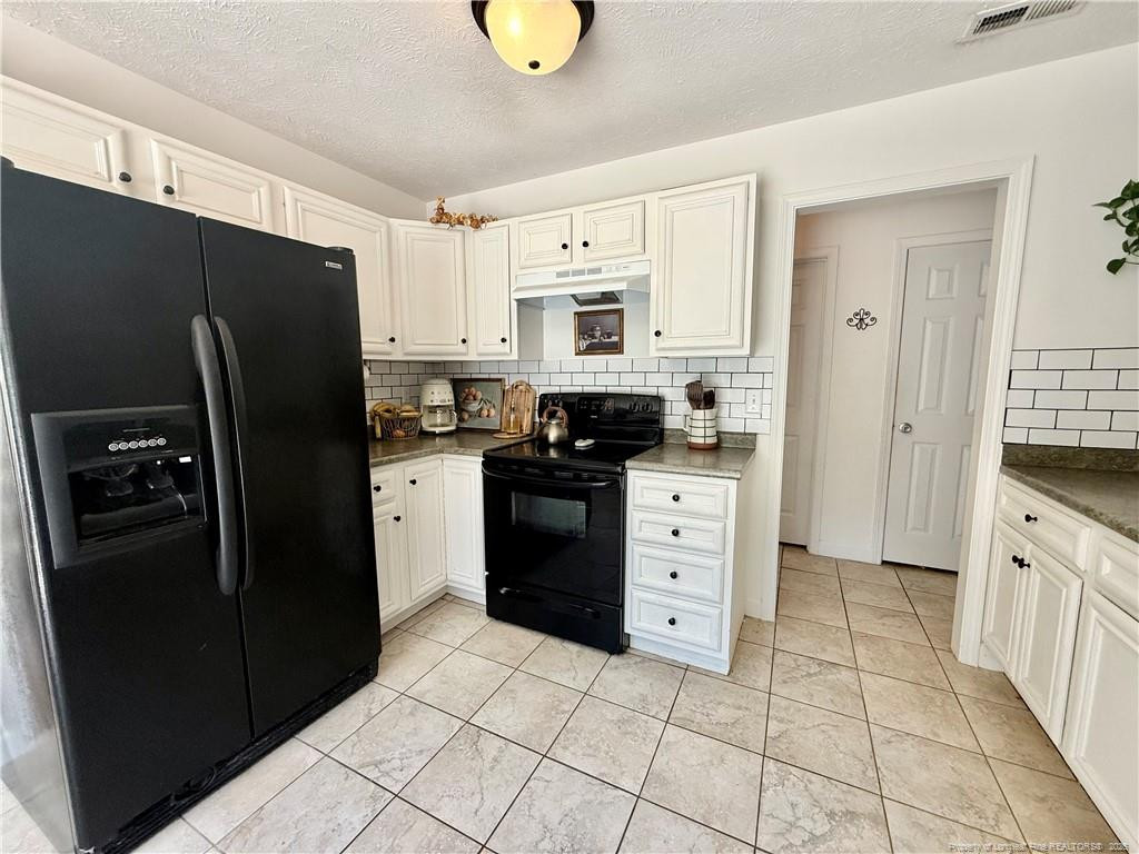 234 Pender Road Spring Lake, NC 28390 - Photo 14 of 39 a kitchen with a refrigerator stove and white cabinets