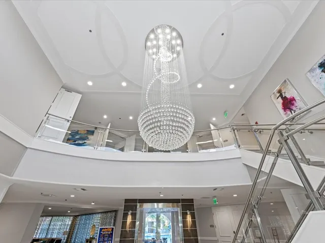 a room with lots of white furniture and a chandelier